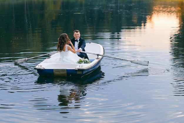 La mariée et le marié dans une barque sur le lac