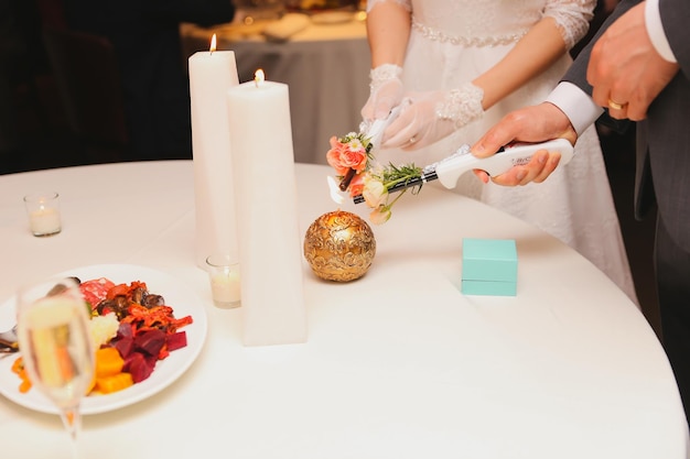 Une mariée et un marié décorent une table avec une bougie et une assiette de nourriture.