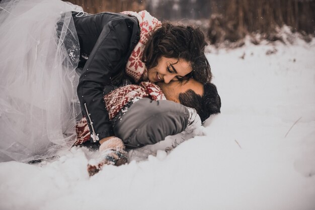 Mariée et le marié en écharpe tricotée lovein et mitaines en hiver et flocons de neige