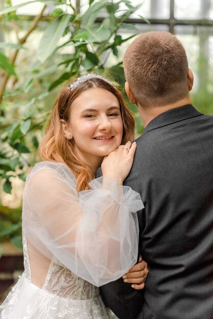 Mariée et le marié étreignant dans la serre