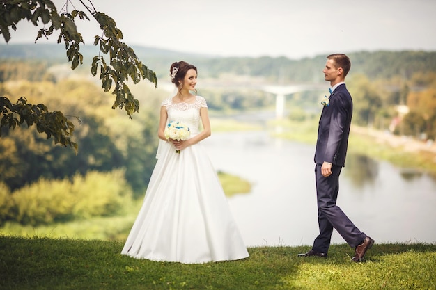 La mariée et le marié sur une haute falaise près de la rivière Promenade des jeunes mariés Le jour du mariage Le plus beau jour d'un jeune couple