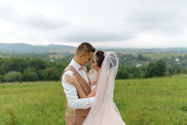 La mariée et le marié lors d'une promenade de mariage. Un couple d'amoureux s'embrasse et se regarde dans les yeux. Fermer.