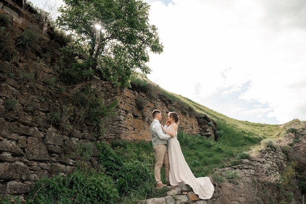 mariée et le marié posant sur le vieux château en ruine.