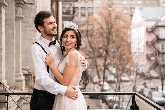 La mariée et le marié s'embrassent sur le balcon. Couple étreignant sur le balcon et profiter de la vie