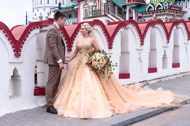 La Mariée Et Le Marié S'embrassent Dans La Rue Dans Le Vieux Kremlin. Jour De Mariage
