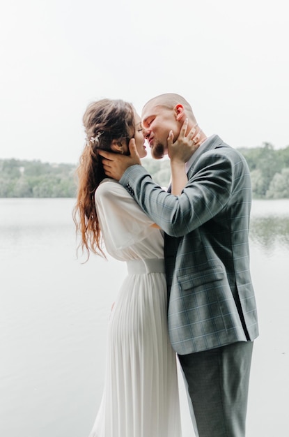 La mariée et le marié s'embrassent et s'embrassent sur le rivage du lac.