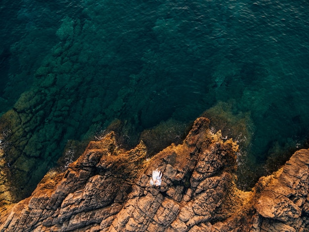 La mariée et le marié s'étreignent sur un rivage rocheux