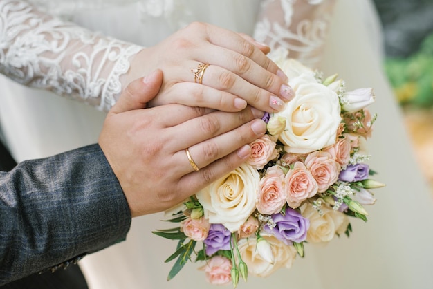 La mariée et le marié se sont mariés et ont montré leurs alliances sur le bouquet délicat de la mariée