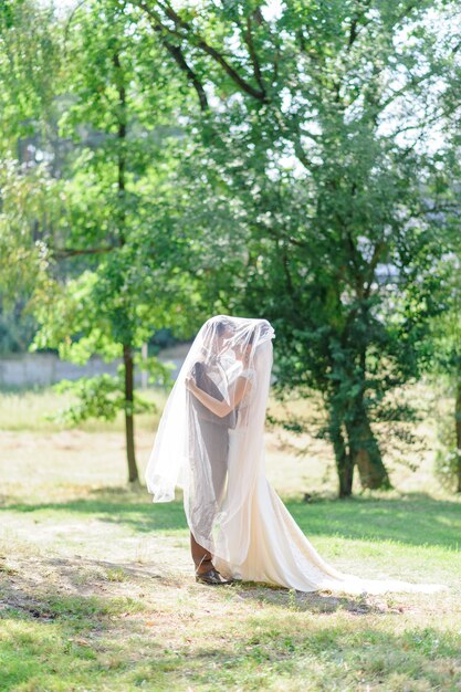 La mariée et le marié se sont réfugiés sous un voile léger.