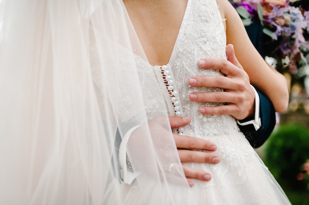 La mariée et le marié se tenant debout sur la nature.