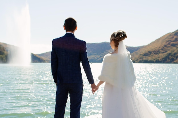 Photo la mariée et le marié se tiennent au fond de la nature vue arrière