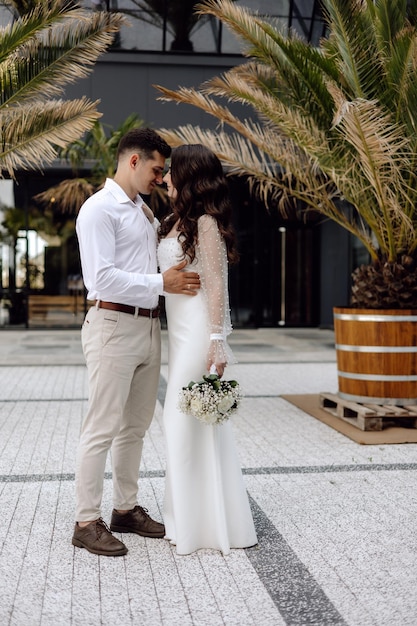 Une mariée et un marié se tiennent devant un baril baril baril avec des palmiers en arrière-plan.