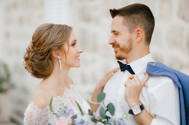 La mariée et le marié se tiennent près d'une belle maison en brique