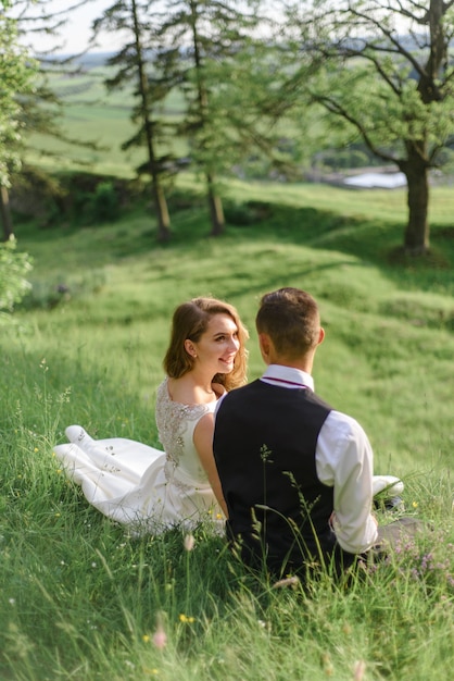 La mariée et le marié sont assis sur l'herbe verte.