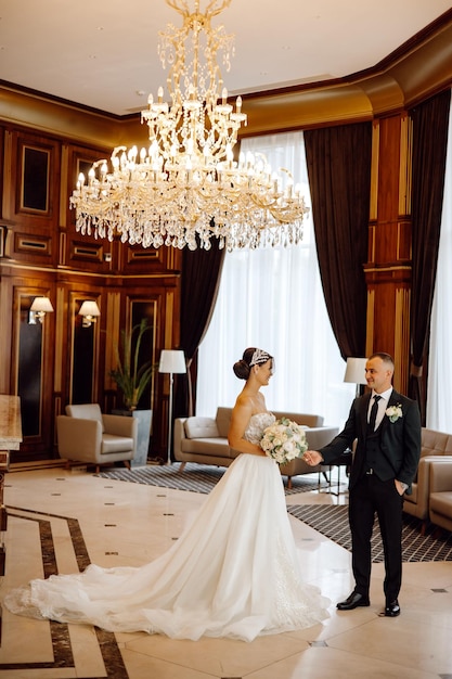 Photo une mariée et un marié sont debout dans une pièce avec un lustre suspendu au plafond