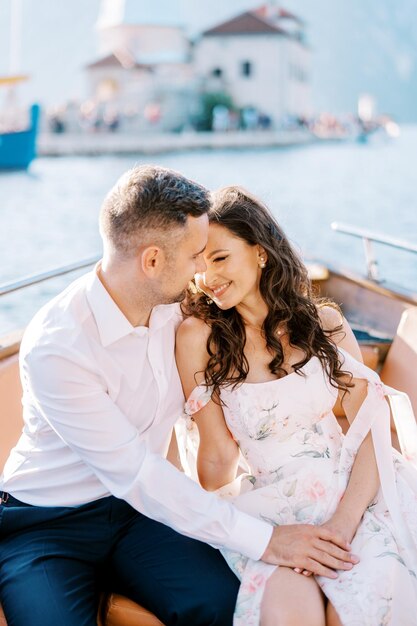 Photo la mariée et le marié sourient en s'embrassant sur un yacht à moteur naviguant sur la mer.