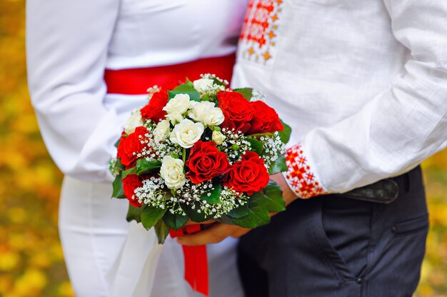 Photo mariée et le marié tenant un bouquet de mariage rouge