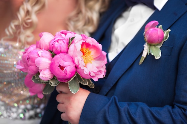 La mariée et le marié tenant un bouquet de pivoines