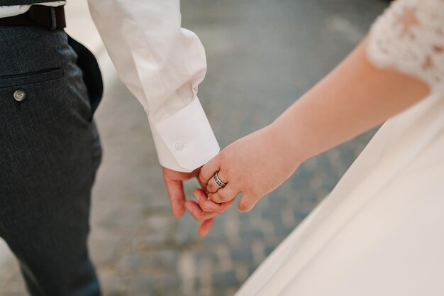 La mariée et le marié vont de l'avant et marchent main dans la main lors d'une promenade dans la rue de la ville Vue de dessous