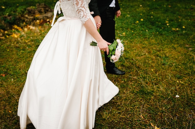 La mariée et le marié vont l'herbe verte après la cérémonie de mariage