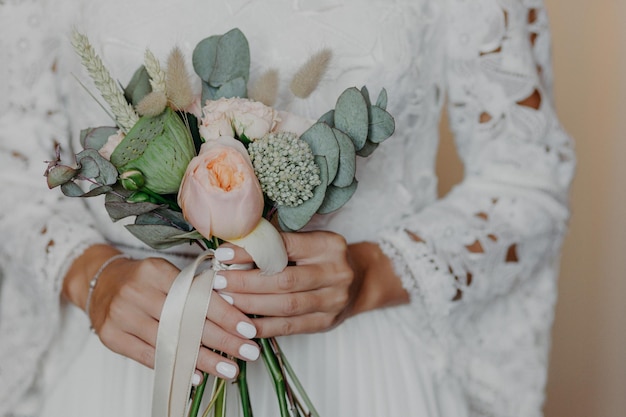 Une mariée méconnaissable avec une manucure tendre tient un beau bouquet porte une robe de mariée blanche Concept de cérémonie d'occasion spéciale