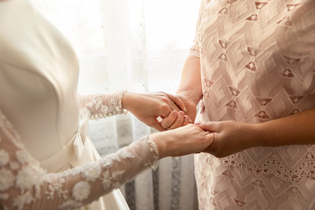 Mariée et mère se tenant la main au jour du mariage