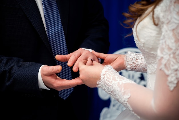 La mariée met l'anneau d'or au doigt du marié pendant la cérémonie de mariage.