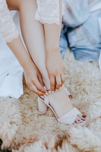 La mariée met de belles sandales de mariage. Fille en sandales à talons un jour de mariage