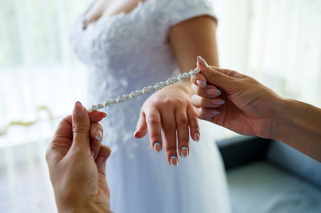La mariée met des bijoux de mariage le jour du mariage