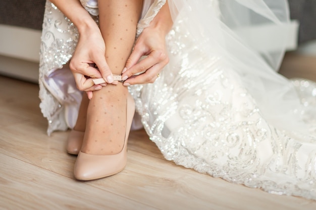 La mariée met des chaussures de mariage