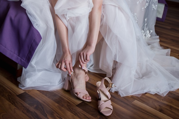 Une mariée met des chaussures de mariage