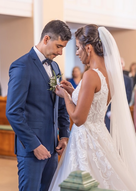 La mariée met une décoration florale sur la poitrine d'un bgroom lors d'une cérémonie de mariage