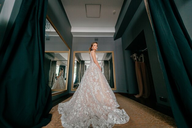 Mariée de mode en robe de mariée blanche posant dans la cabine d'essayage