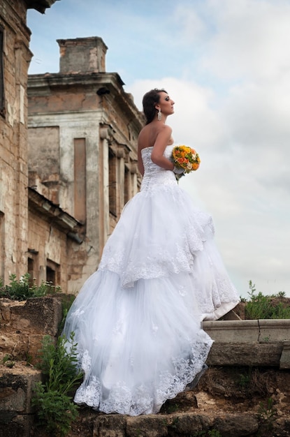 Mariée avec panier de dentelle et ventilateur dans ses mains dansant devant des ruines