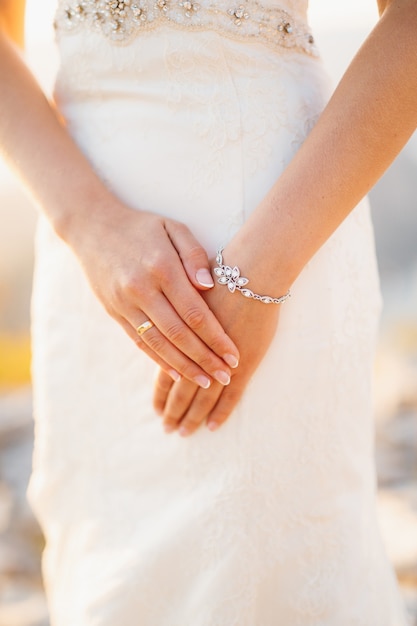 La mariée a plié ses mains avec une bague de mariage à son doigt et un gros plan de bracelet