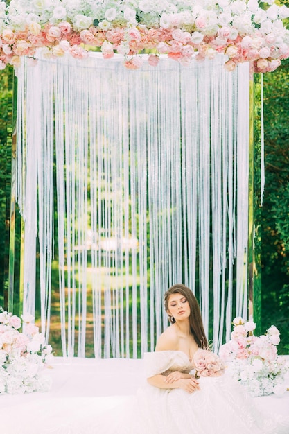 Mariée près de l'arche de mariage avec des fleurs