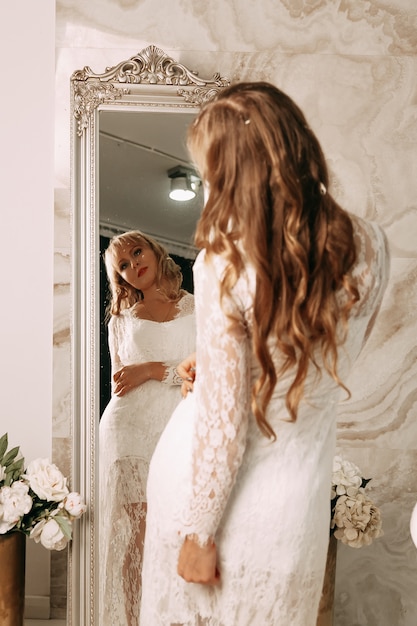 Mariée en robe blanche élégante regardant dans le miroir. Matin des préparatifs de la mariée.