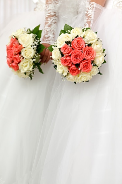 La mariée en robe blanche lors d'une cérémonie de mariage avec un bouquet de roses.