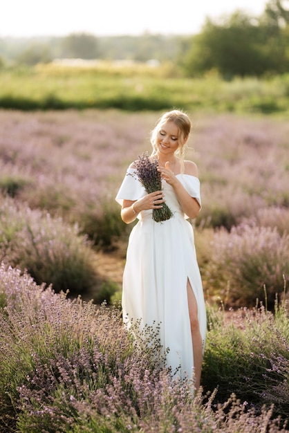 La mariée en robe blanche marche sur le champ de lavande