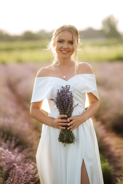 La mariée en robe blanche marche sur le champ de lavande