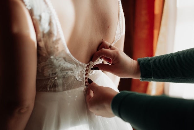 Mariée en robe blanche mise sur la robe vue arrière close up