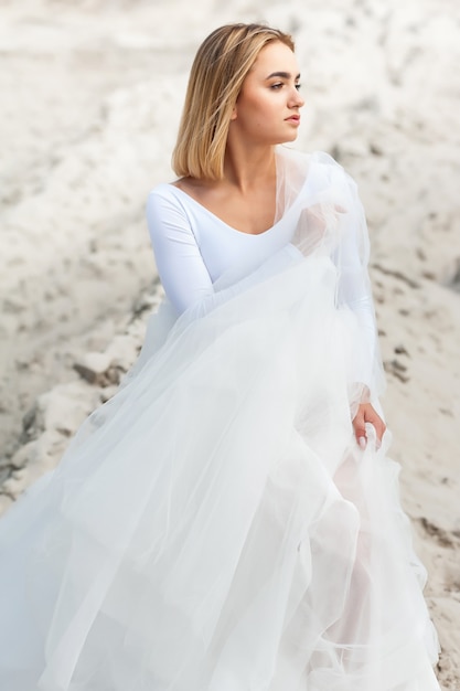 Mariée en robe blanche en plein air sur le sable et fond de ciel bleu