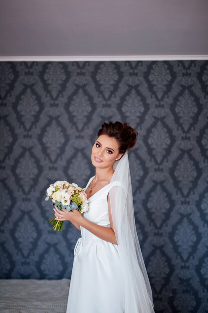 Mariée en robe blanche posant à l'intérieur