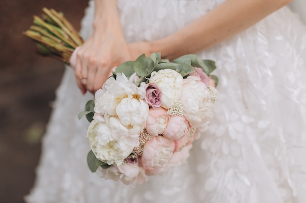 Mariée en robe blanche tenant son bouquet de mariée