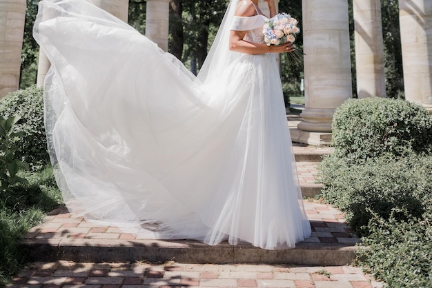 Mariée en robe de mariée et bouquet dans le parc