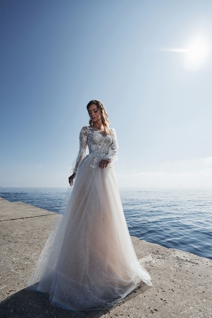 Mariée en robe de mariée sur la plage au bord de la mer