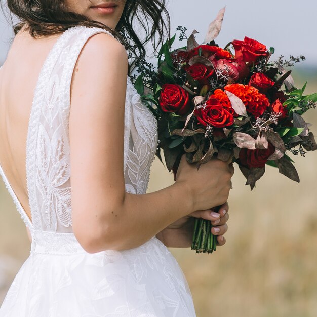 Mariée en robe de mariée et tenant le bouquet de mariée