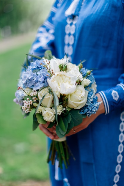 Mariée en robe nationale ukrainienne tenant le bouquet