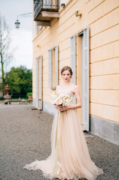 Mariée en robe rose avec un bouquet de fleurs dans la rue