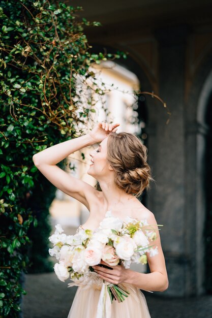 Mariée en robe rose avec un bouquet de fleurs a mis sa main sur son front